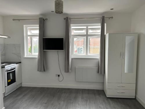 Modern Loft Studio kitchen at Starlet Property London with stainless steel stove, white cabinetry, windows, wall-mounted TV,