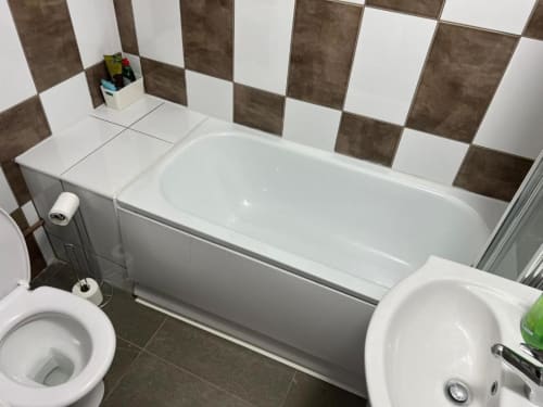 Modern bathroom in Starlet Property London Loft Studio with white bathtub, toilet, bidet, and brown and white checkered tile