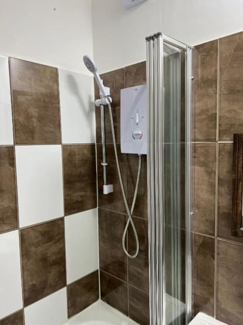 Modern bathroom in Starlet Property London hotel with brown and white tile walls, walk-in shower enclosure, and white
