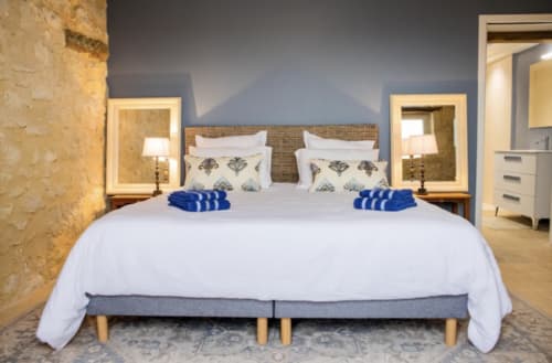 Chambre moderne du Château Haut Clarise aux accents bleus, literie blanche et mobilier contemporain