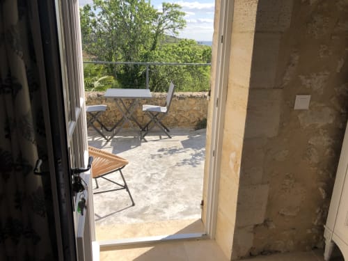 Portes de terrasse ouvertes offrant une vue sur la campagne et des sièges extérieurs au Château Haut Clarise à Belvès-de-Castillon, France