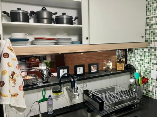 Cozinha do Hostel New Ipanema com armários brancos, bancada preta, fogão, pia com escorredor e azulejo verde na parede