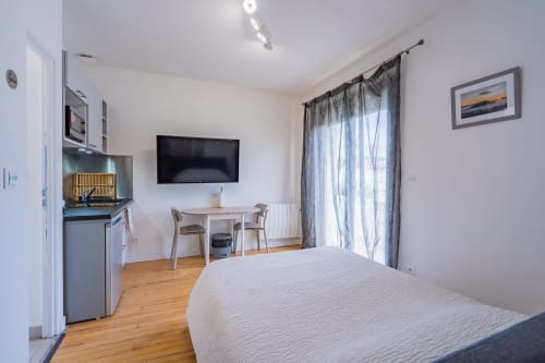 Studio moderne à Toulouse avec lit, kitchenette, télévision et balcon vue sur la ville