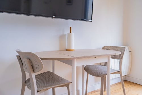 Salle à manger moderne à Toulouse avec table blanche, chaises beige, téléviseur mural et parquet