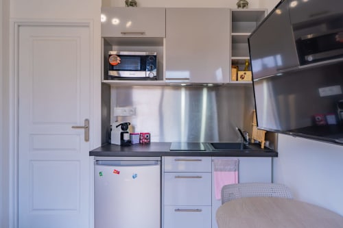 Kitchenette moderne à Toulouse avec électroménagers inox, plan de travail noir et coin repas