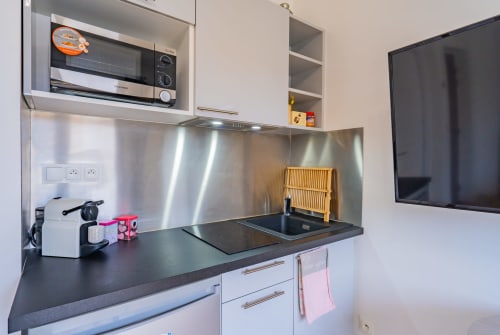 Kitchenette moderne à Toulouse avec dosseret inox, plaque à induction, micro-ondes et plan de travail noir