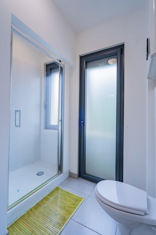 Salle de bain moderne avec douche à l'italienne, toilettes et tapis de bain vert à l'appartement Room In Toulouse à La Salvetat-Saint-Gilles