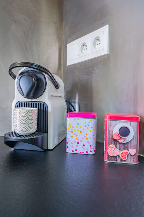 Machine à café Nespresso avec des boîtes de rangement colorées sur le plan de travail d'un appartement à Toulouse