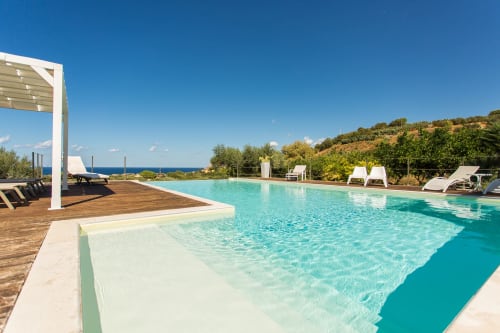 Luxury poolside at Villa Maria with turquoise infinity pool, sea view, loungers, and Mediterranean garden in Valderice,