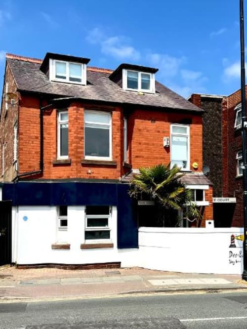 Dee-8 apartment in West Kirby, Wirral - red brick townhouse with garden view and blue storefront entrance
