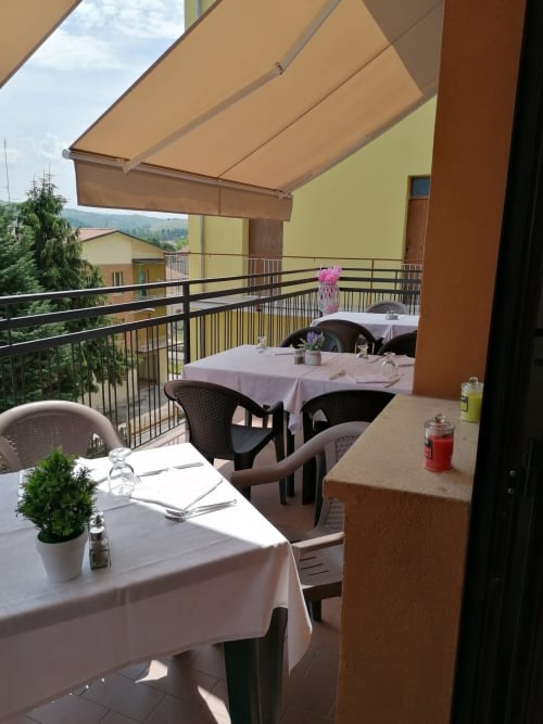 Terrazza esterna dell'Hotel Eden a Vignola con tavoli da pranzo, tenda retrattile e vista sulle montagne