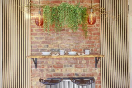 Dee-8 apartment fireplace with wooden shelf, potted plants, pendant lights, and tableware in West Kirby