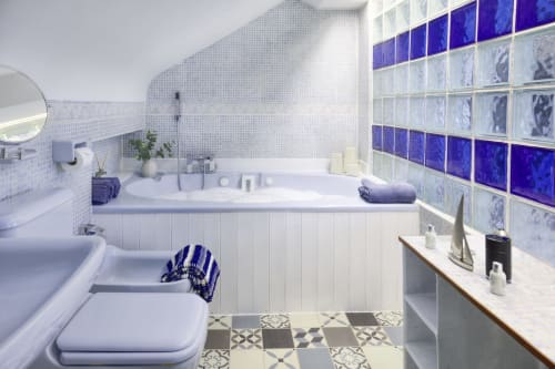 Modern bathroom at Dee-8 apartment in West Kirby with blue mosaic tiles, white suite, and geometric floor pattern