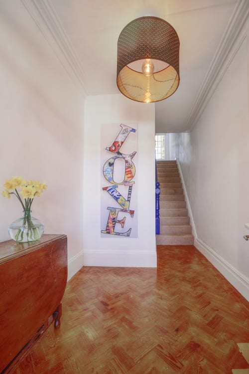Modern hotel hallway at Dee-8 with 'LOVE' wall art, wooden furniture, yellow flowers, and pendant lighting