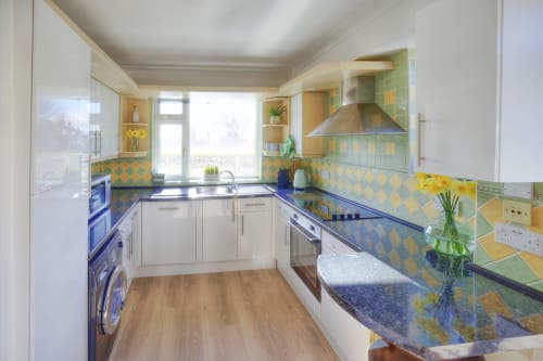Modern kitchen at Dee-8 hotel in West Kirby with white cabinetry, blue countertops, and yellow-green diamond tile backsplash