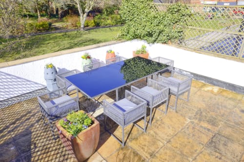 Modern patio seating area at Dee-8 hotel in West Kirby with blue table, wicker chairs, and potted plants