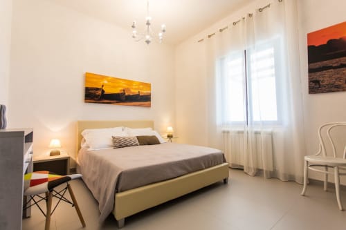 Modern bedroom at Villa Maria, Sant'Andrea, with yellow headboard, sea view artwork, and bright windows overlooking the sea