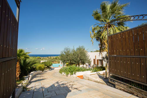 Villa Maria entrance with sea view, palm trees, pool, and Mediterranean landscape in Sant'Andrea, Sicily