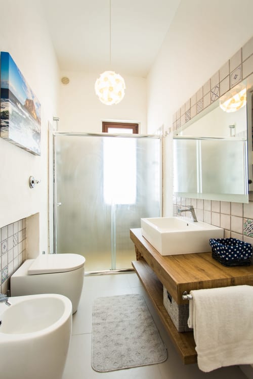 Modern bathroom in Villa Maria with vessel sink, glass shower, toilet, bidet, and wooden vanity in Sant'Andrea, Sicily