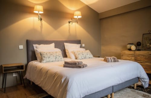 Chambre moderne du Château Haut Clarise avec lit king-size, luminosité chaleureuse et mobilier contemporain