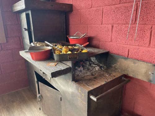 Churrasqueira de tijolos ao ar livre na villa Paraíso nas Montanhas em Campos do Jordão com panelas de cozimento e vegetais assados