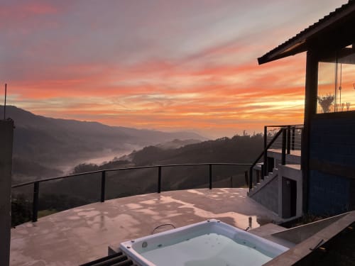 Deck da villa na montanha ao pôr do sol com banheira de hidromassagem com vista para vales enevoados em Campos do Jordão