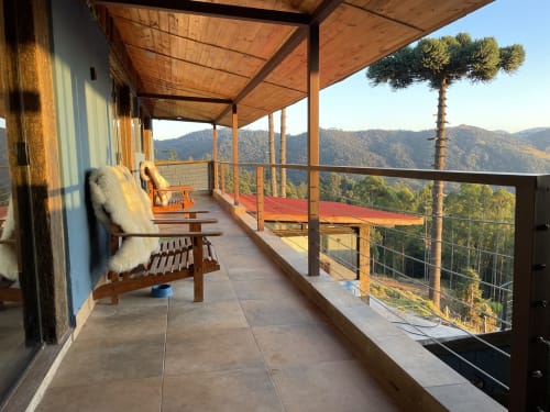 Deck da villa de montanha em Paraíso nas Montanhas com cadeiras de madeira, grade metálica e vistas do vale florestado em Campos do Jordão