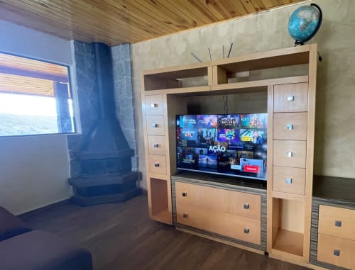 Sala de estar moderna na villa Paraíso nas Montanhas com painel de entretenimento em madeira, TV streaming e vistas para as montanhas