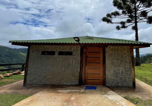 Villa de pedra com telhado de metal verde em Paraíso nas Montanhas, Campos do Jordão, com vista para a paisagem montanhosa