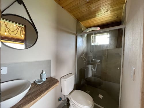 Banheiro moderno da vila Paraíso nas Montanhas com ducha aberta, pia com bancada e teto de madeira em Campos do Jordão