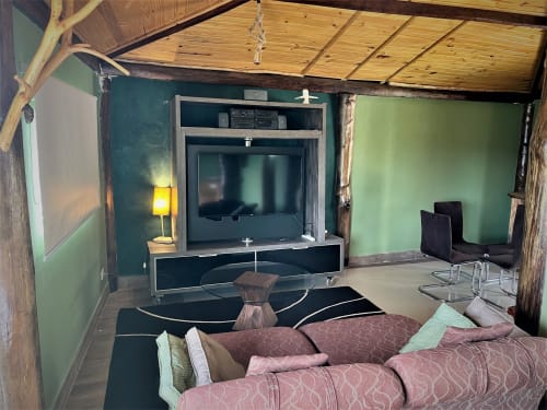 Sala de estar moderna da villa Paraíso nas Montanhas, Campos do Jordão, com assentos rosa, paredes verdes e TV na parede