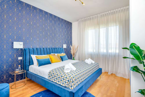Lussuosa camera Art Déco blu in SleepWithMe B&B Pisa con carta da parati geometrica, letto in velluto e vista sulla città
