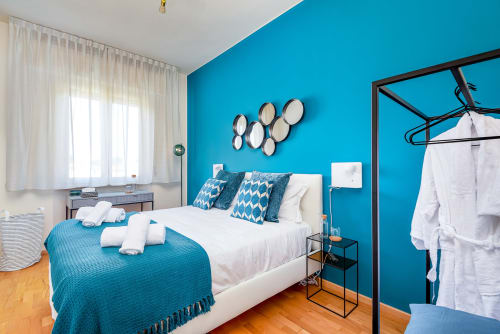 Camera da letto turchese nella luxury B&B SleepWithMe Pisa, con biancheria bianca, specchi decorativi e pavimenti in legno