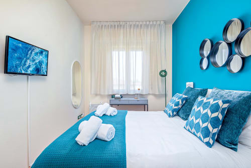 Camera da letto di lusso turchese moderno presso SleepWithMe B&B a Pisa con vista sulla città, biancheria bianca, asciugamani arrotolati e decorazioni