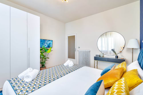 Camera lussuosa SleepWithMe B&B Pisa in stile Art Déco con cuscini gialli, dettagli blu, specchio rotondo e vista sulla città