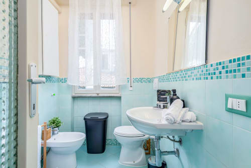 Bagno turchese in esclusiva suite Art Decò di lusso a Pisa con finiture moderne e finestra con vista sulla città