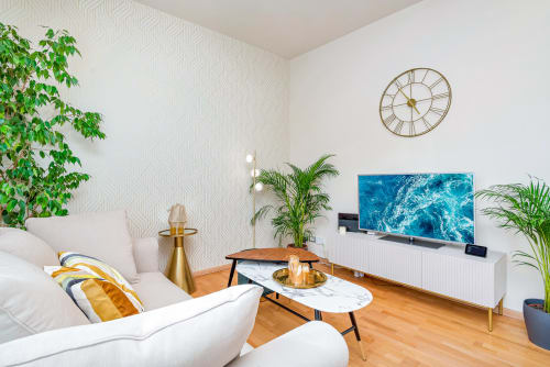 Lussuoso appartamento moderno a Pisa con divano bianco, tavolino in marmo, TV a parete con onde oceaniche, orologio dorato e