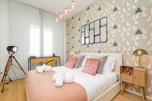 Camera da letto di lusso moderno in B&B a Pisa con carta da parati geometrica, mobili mid-century, biancheria rosa e lampade a sospensione