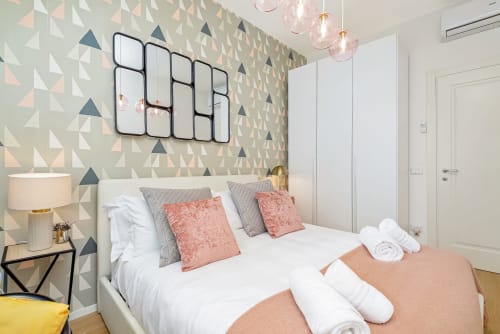 Camera da letto di lusso moderno al SleepWithMe B&B di Pisa con carta da parati geometrica, lampade a sospensione e accenti corallo