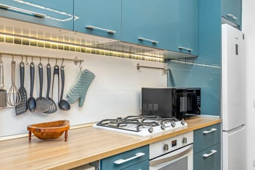 Cucina turchese moderna con banconi in legno, fornello a gas e utensili appesi al SleepWithMe Luxury B&B di Pisa