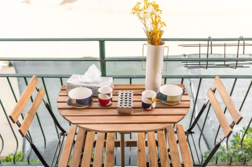 Angolo colazione in balcone presso SleepWithMe Luxury B&B a Pisa con mobili in legno, tazze bianche e fiori secchi con vista su