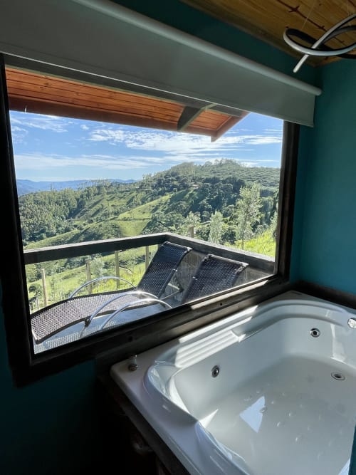 Banheiro luxuoso com banheira de imersão com vista para as montanhas verdejantes de Campos do Jordão em Paraíso nas Montanhas