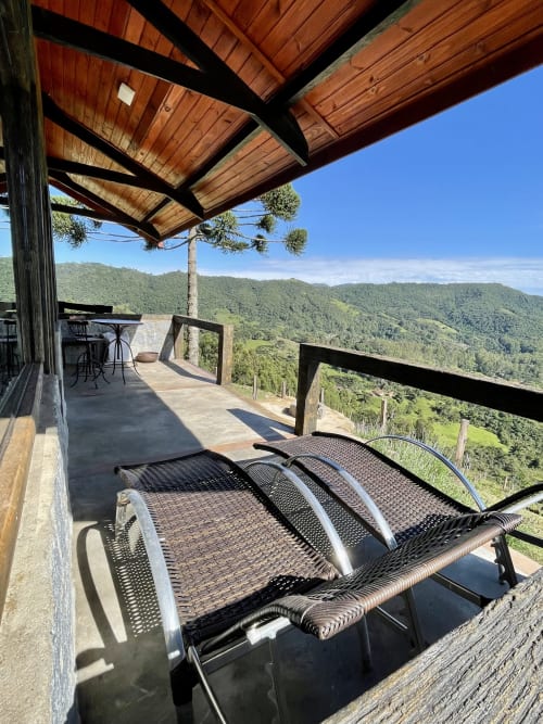 Terraço da vila na montanha em Paraíso nas Montanhas com espreguiçadeiras, pérgula de madeira e vistas do frondoso vale de Campos do Jordão