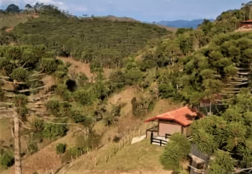 Villa Paraíso nas Montanhas com telhado vermelho, aninhada na exuberante paisagem montanhosa de Campos do Jordão