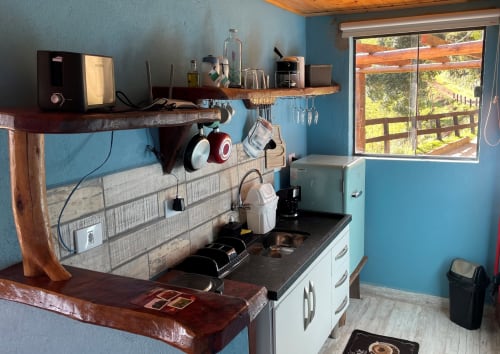 Cozinha moderna com paredes azuis, prateleiras de madeira e vista das montanhas na villa Paraíso nas Montanhas, Campos do Jordão