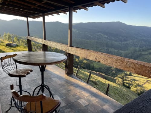 Terraço da villa na montanha em Paraíso nas Montanhas com mesa redonda, cadeiras e vistas panorâmicas do vale de Campos do Jordão