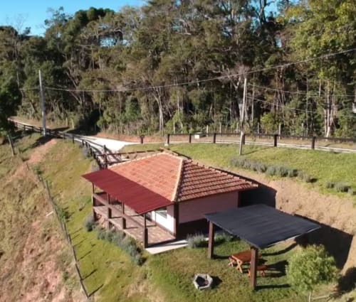 Villa Paraíso nas Montanhas com telhado vermelho, painéis solares e vista da floresta montanhosa em Campos do Jordão
