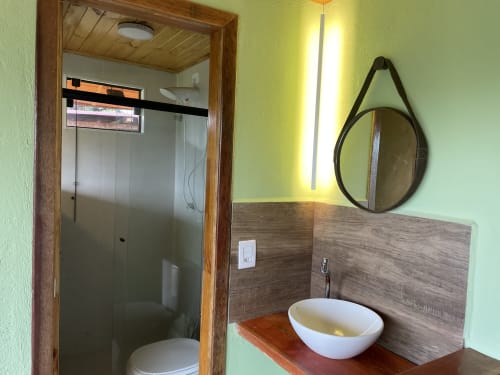 Banheiro moderno com Cuba de cerâmica branca, espelho redondo e box de vidro na villa Paraíso nas Montanhas em Campos do