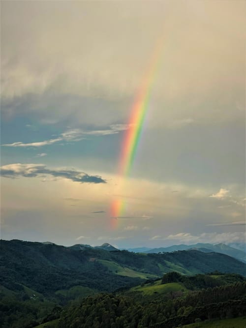 Arco-íris duplo sobre montanhas verdes na pousada Paraíso nas Montanhas, Campos do Jordão com vista cênica das serras