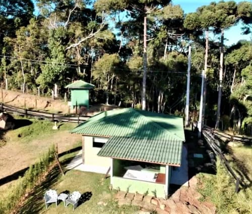 Vila com telhado verde em Paraíso nas Montanhas, Campos do Jordão, entre pinheiros e paisagem montanhosa